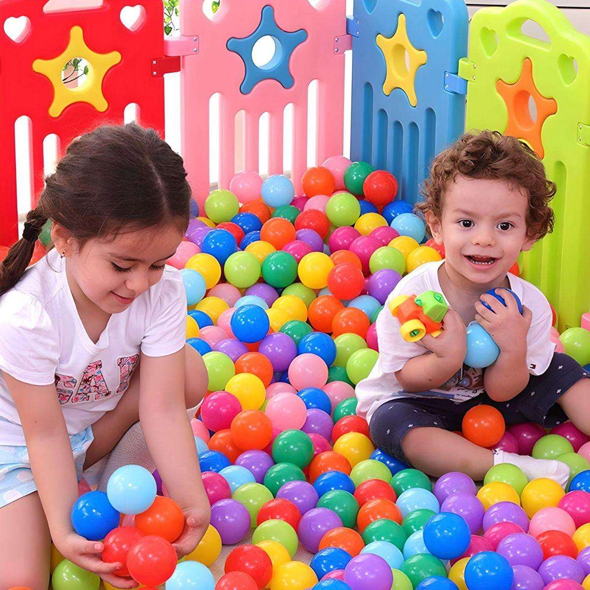 Two children playing in a colorful ball pit filled with BabiePlay Colourful Odyssey Ball Pit Balls in vibrant red, blue, green, purple, and orange colors.