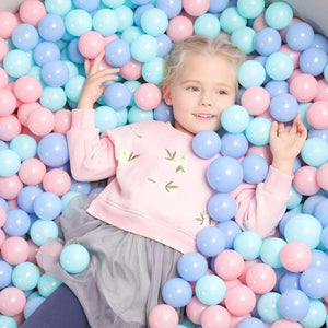 Child playing in BabiePlay Colourful Odyssey Ball Pit Balls in pastel pink, blue, and purple colors