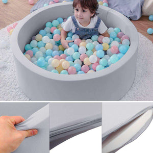 Child playing in BabiePlay Ultimate Foam Ball Pit with pastel-colored balls and removable cover.