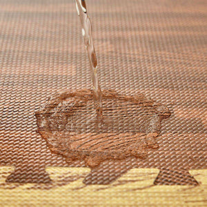 Close-up of BabiePlay Wood Grain Play Mat showing water-resistant EVA foam surface with water pouring on it.