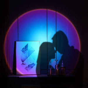 Glowly Sunset Lamp projecting colorful romantic silhouette lighting on wall with decorative art and bottles