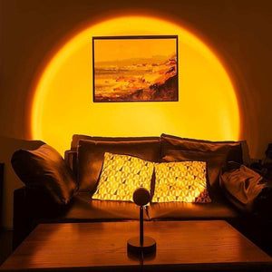 Glowly Sunset Lamp projecting warm orange light over sofa and wall art creating cozy ambiance