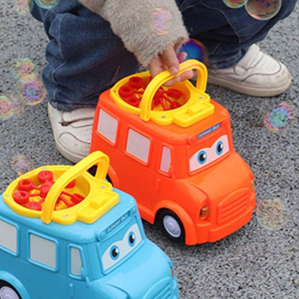 Children playing with colorful school bus bubble blower toys creating bubbles outdoors