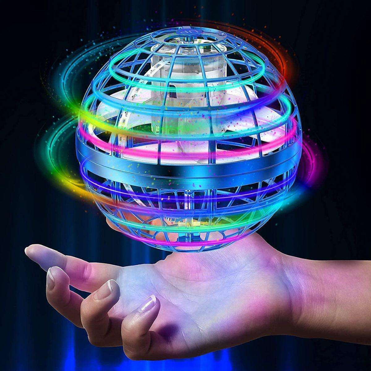 Kidst flying drone with colorful RGB lights spinning above a hand in dark background