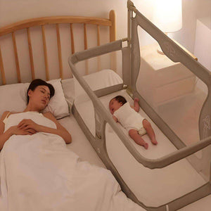 Mother sleeping beside baby secured in Toddly NightNest Bedside Rail attached to bed