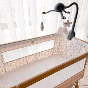 Baby Bassinet & Bedside Co-Sleeper with beige linen-cotton fabric, breathable mesh sides, wood-grain frame and hanging sensory toys