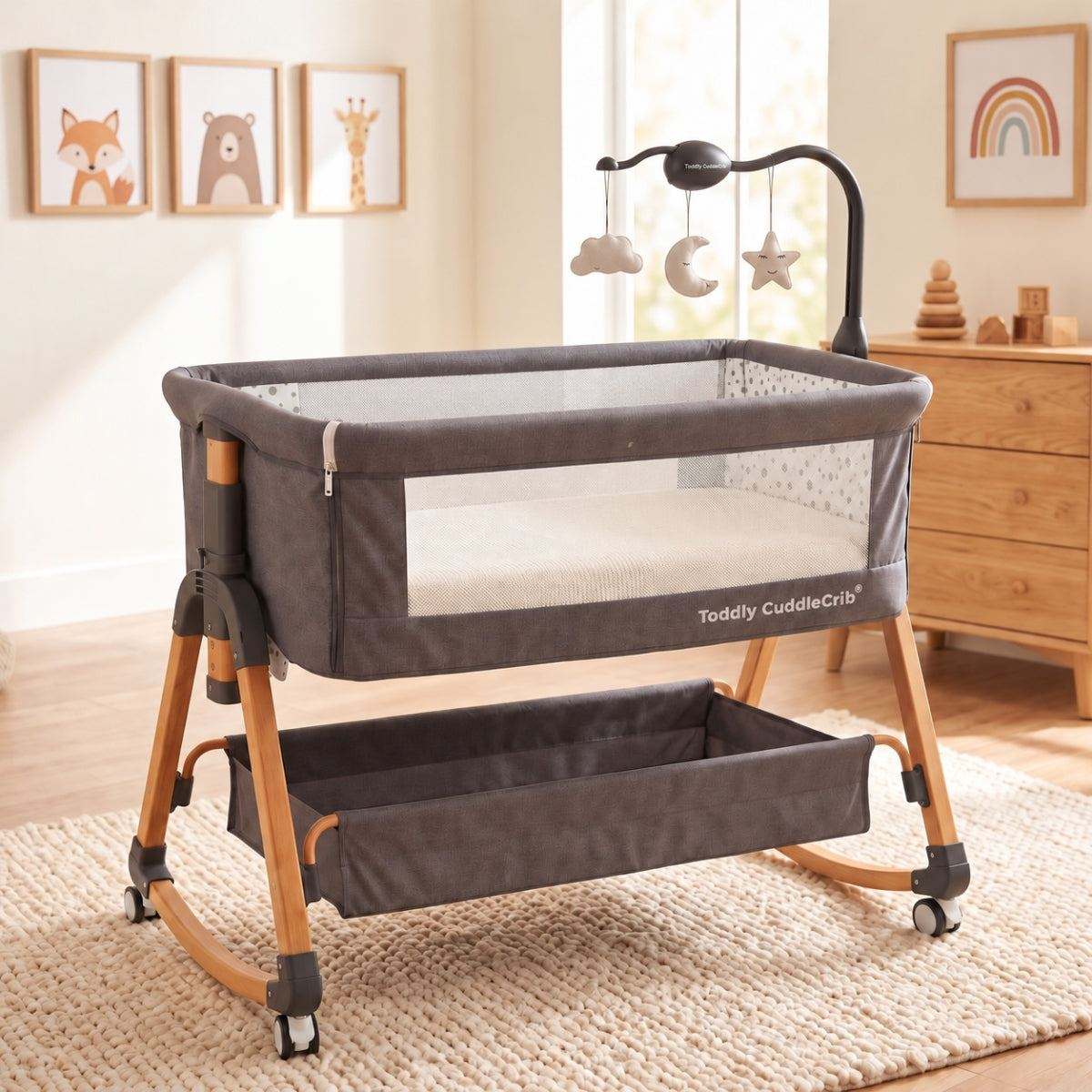 Baby Bassinet & Bedside Co-Sleeper in charcoal grey fabric with wood-grain finish steel frame, mesh side panels, and hanging toy mobile