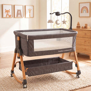 Baby Bassinet & Bedside Co-Sleeper in charcoal grey fabric with wood-grain finish steel frame, mesh side panels, and hanging toy mobile